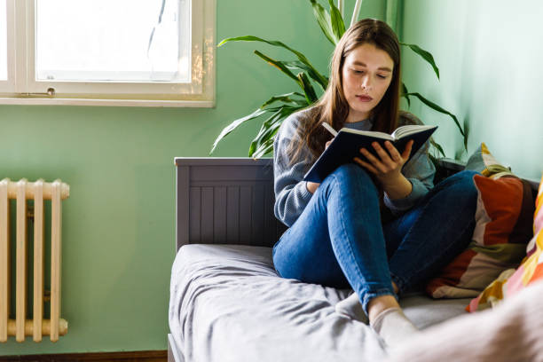 istock Serious young woman sitting on bed and writing in her diary 1371044927