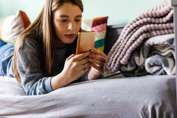 istock Young woman lounging on her bed and using smart phone 1371044929