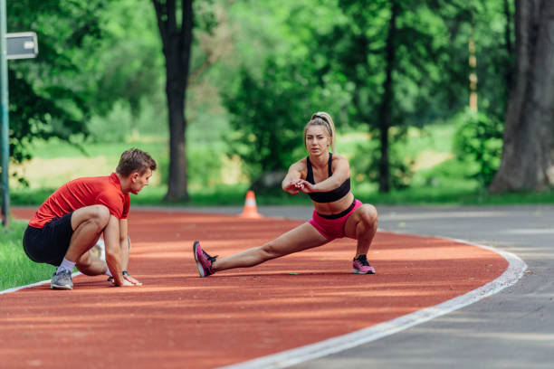 istock Young couple stretching before starting their morning jogging routine on a tartan track at the park. 1371045965