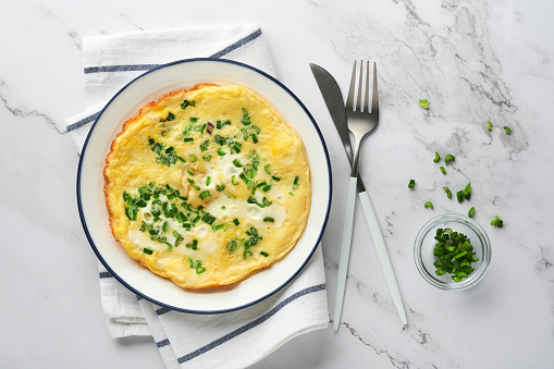Omelette or frittatas with green onions or young greenery and mozzarella on white marble table background. Healthy food concept. Breakfast. Copy space. Top view. Mock up.
