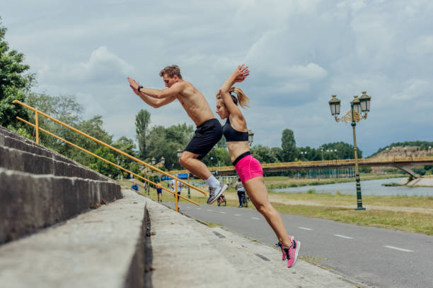 imagem de visão lateral de casal esportivo ativo pulando em escadas em um parque - tall short men women - fotografias e filmes do acervo