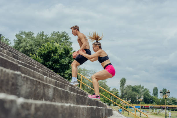 imagem de visão lateral de casal esportivo ativo pulando em escadas em um parque - tall short men women - fotografias e filmes do acervo