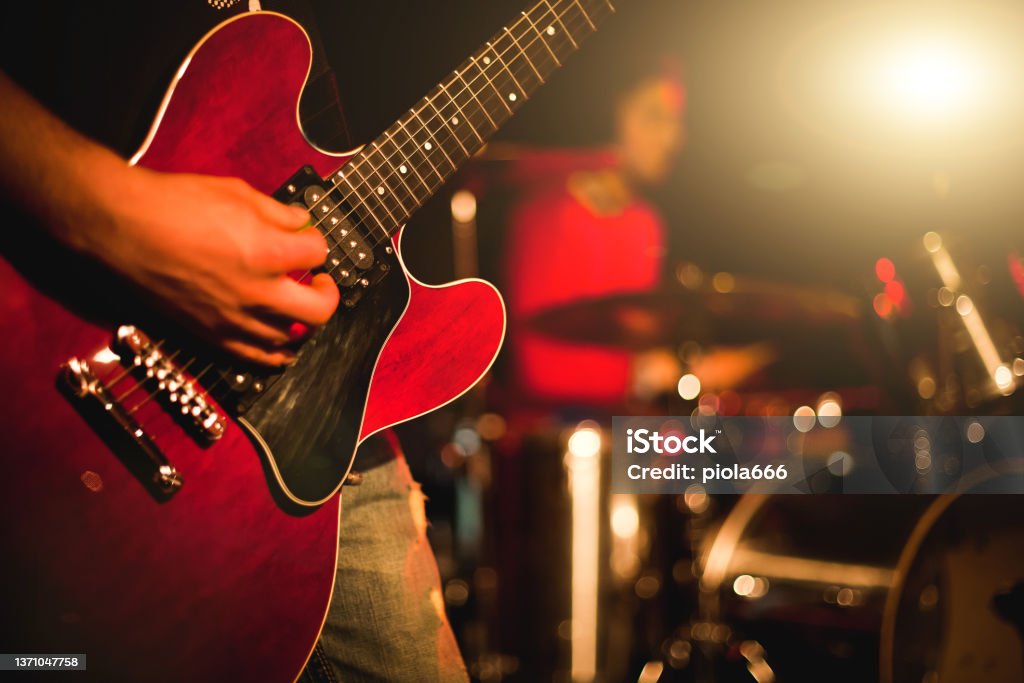Indie rock guitarist playing guitar in a live show with stage lights Rock guitarist playing guitar in a live show, lights and smoke Music Stock Photo