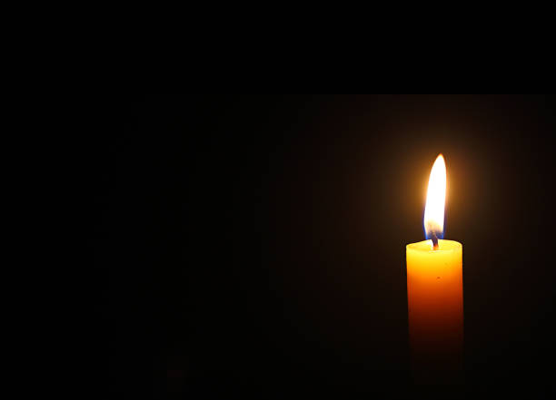 istock Close up single yellow candle light and flame on black background 1371048389