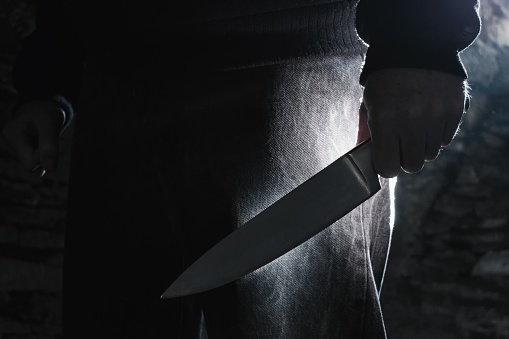 Foto oscura de un hombre sosteniendo un cuchillo grande, concepto de crimen. photo