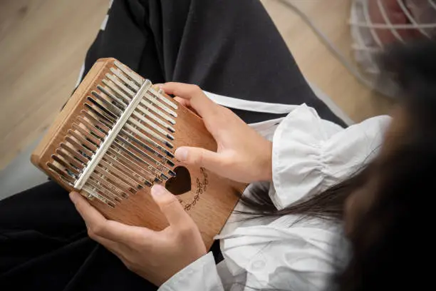 Hand of an Asian girl playing a wooden Kalimba instrument