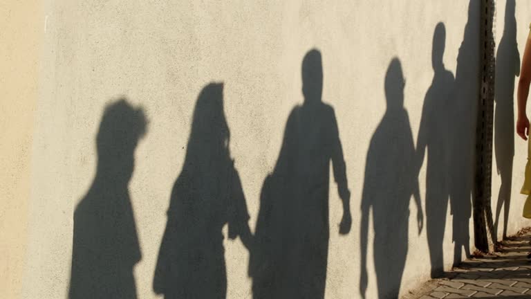 Shadows of walking crowd of people on a wall in slow motion