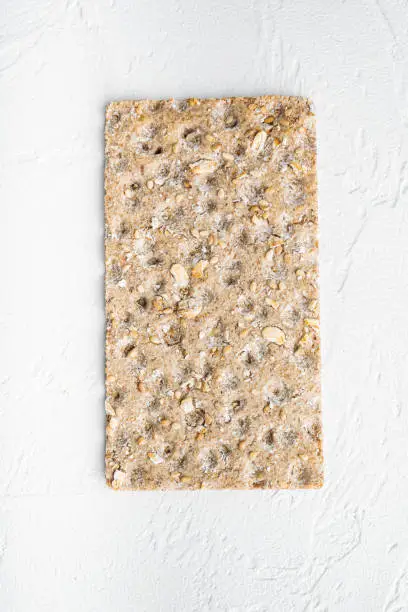 Whole grain crisp bread set, on white stone table background, top view flat lay