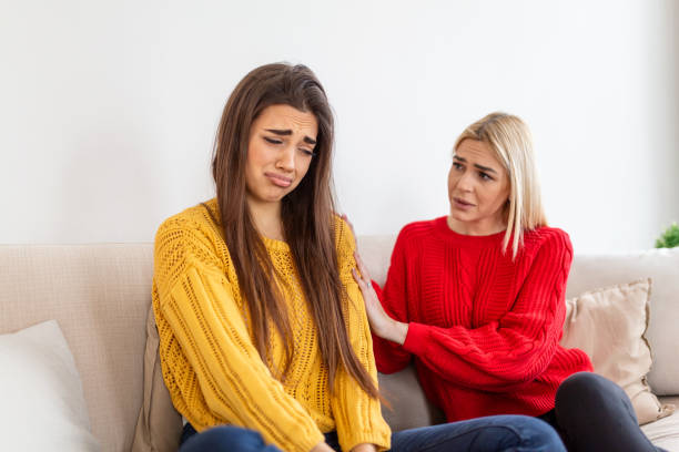 amie essayant de calmer son amie. femme en pleurs. jeune femme partageant son problème avec une amie. femme en dépression. femme réconfortante son ami triste assis sur un canapé dans le salon à la maison - child grief mourner disappointment photos et images de collection