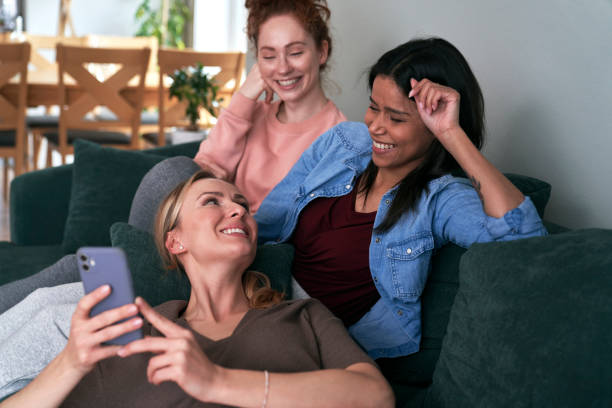 istock Three best caucasian friends smiling while browsing smart phone   on the sofa 1371054259