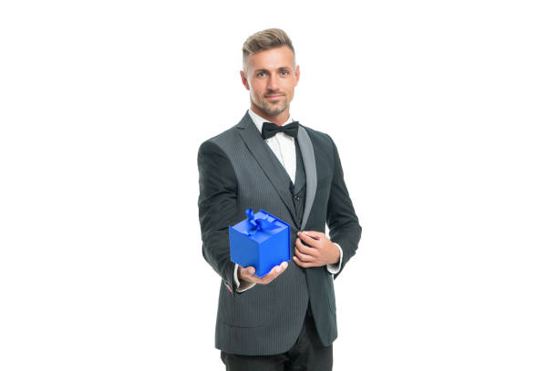 istock cheerful man in tuxedo and bow tie hold present box isolated on white background 1371056843