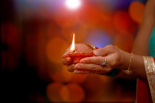 Young woman holding oil lamp in hand on Diwali Festival. Diwali is a festival of lights and one of the major festivals celebrated by Hindus, Jains, and Sikhs. The festival usually lasts five days and is celebrated during the Hindu lunisolar month Kartika.