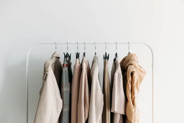 Spring capsule clothes of beige color palette on a rack over wwhite background. Closeup