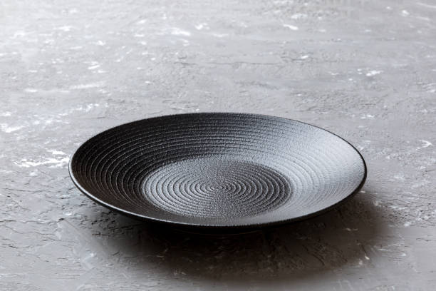 istock Perspective view of empty black plate on cement background. Empty space for your design 1371058363