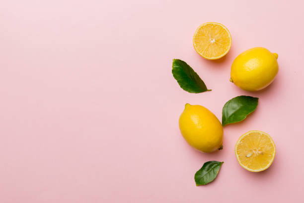 istock Many fresh ripe lemons with green leaves on colored background, top view, space for text 1371058421