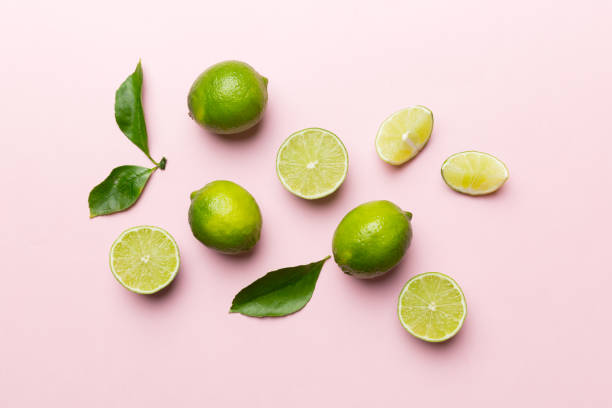 Lime fruits with green leaf and cut in half slice isolated on white background. Top view. Flat lay with copy space stock photo