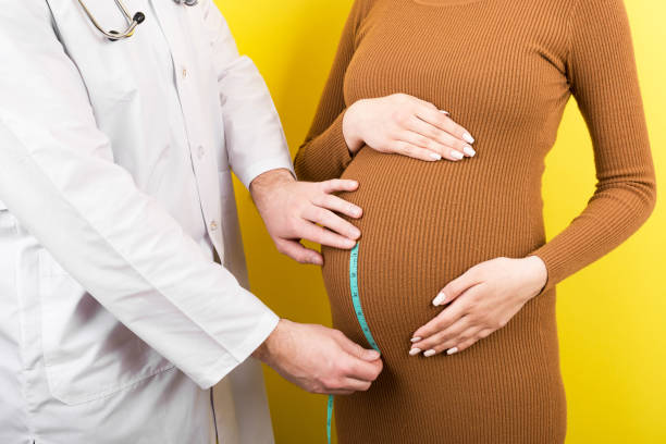 felice bella giovane donna incinta che si tocca la pancia nuda mentre un medico la sta misurando - 40 weeks foto e immagini stock