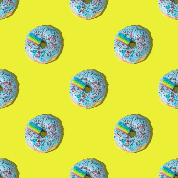 istock A repeating pattern of blue donuts with a rainbow on a yellow background. Flat lay 1371059939