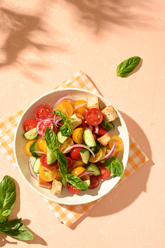Tuscan Panzanella with tomatoes and bread on sunny background. Top view. Traditional Italian cuisine. Vegetarian panzanella salad. Mediterranean healthy food.