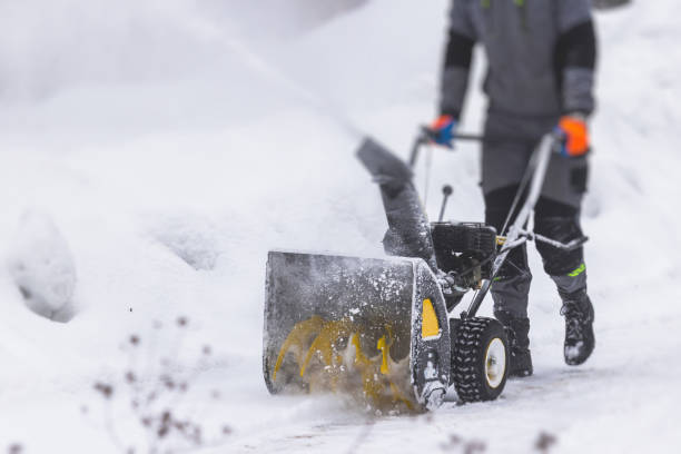 Process of removing snow with portable blower machine, worker dressed in overall workwear with gas snow blower removal on the street during winter stock photo