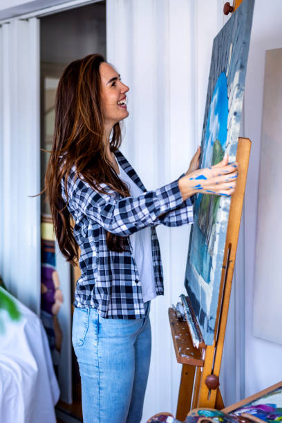 istock Happy young woman paints landscape on canvas in workshop 1371066229