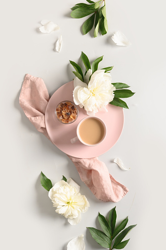 Breakfast with coffee cup and white peonies flowers on gray bckground. View from above, flat lay. Concept nostalgia, memories, tenderness.
