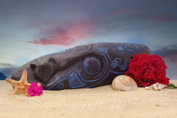 wooden tiki mask on sand with flowers and blue sky background - shell sea souvenir island imagens e fotografias de stock