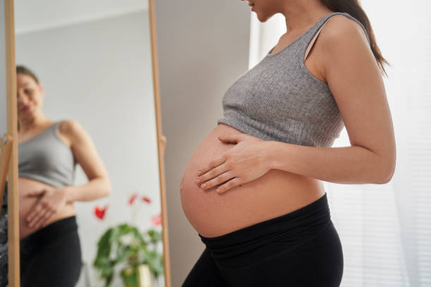 istock Caucasian woman in advanced pregnancy browsing herself in the mirror 1371069103