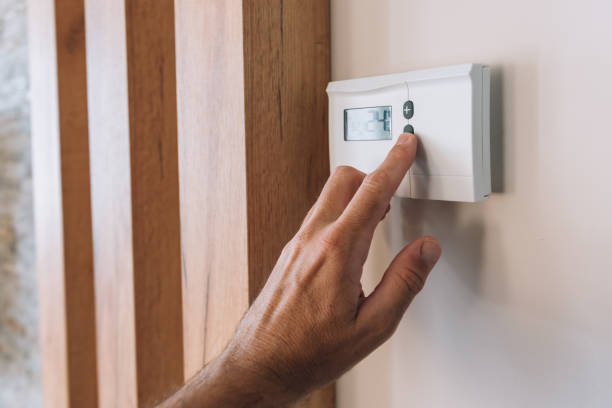 istock Male hand pushing the button of home heating and cooling system control unit 1371069633