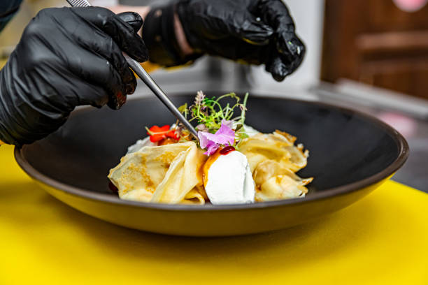 istock Chef's hands in gloves cooking crepe pancake on plate in kitchen 1371070238