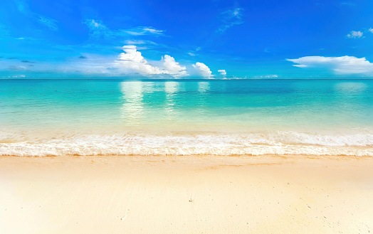 Blue summer sky, white clouds reflected in turquoise clear water ocean.