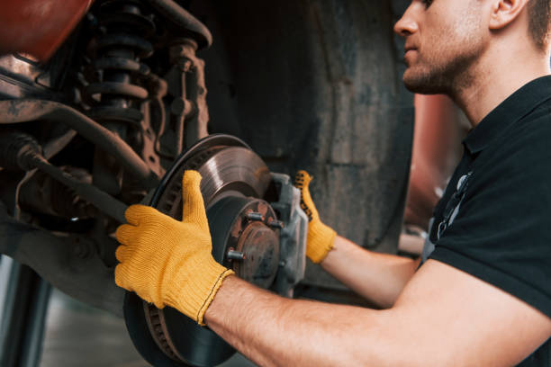 istock Fixing breaks. Man in uniform is working in the auto service 1371072936