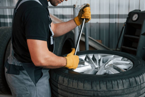 istock Working with broken wheel. Man in uniform is working in the auto service 1371073694