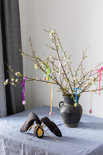 Blooming cherry branches decorated with colorful ribbons with Easter eggs, Happy Easter, table setting, napkin and egg rabbit