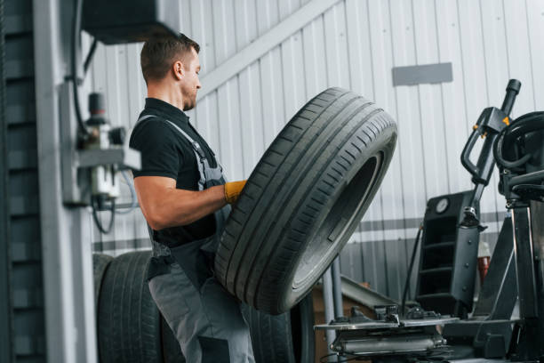 istock Walking and holding tyre. Man in uniform is working in the auto service 1371073764