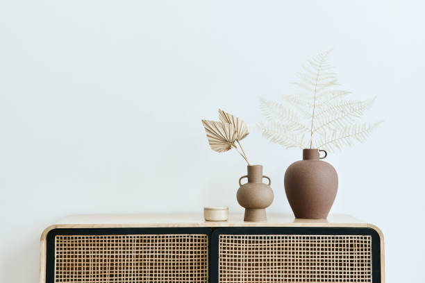 istock Modern scandinavian home interior with design wooden commode, dried leafs in ceramic vases and personal accessories in stylish home decor. Template. Copy space. White walls. 1371075546
