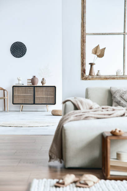 istock Stylish composition of living room with design beige sofa, wooden stool,  commode, book, decoration, furniture, window and elegant personal accessories. Modern home decor. Open space. Template. 1371076048