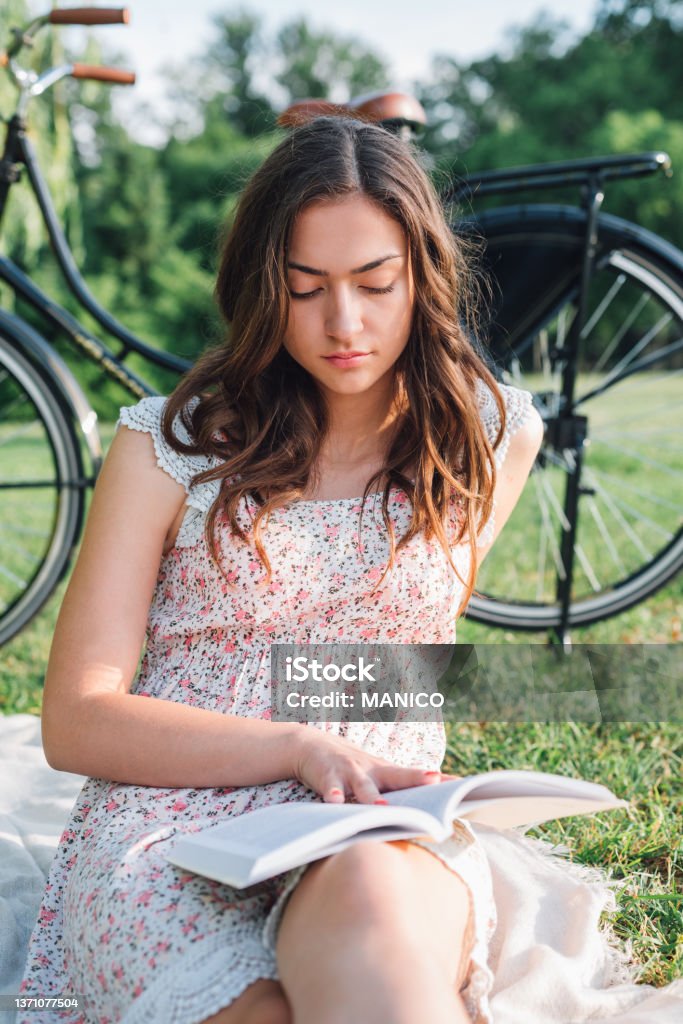 Woman Reading A Book In A Park Close up of beautiful young woman reading a book in a park. Picnic Stock Photo