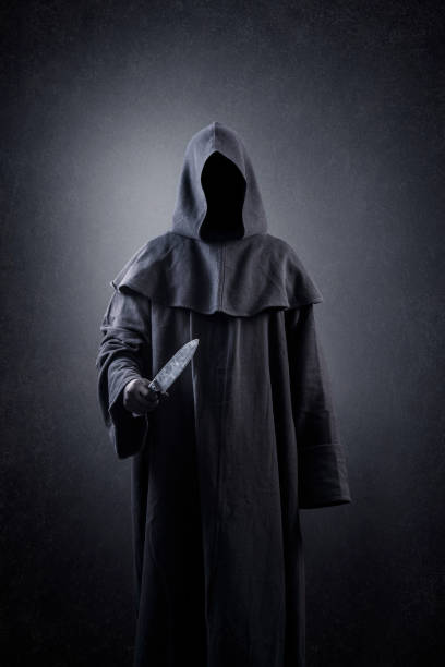 istock Hooded man with old knife in the dark 1371077620