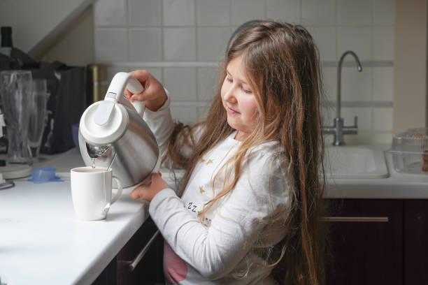 小さな女の子は自宅で朝食を作るのに役立ちます。家族、検疫、家庭教育の概念。 - tea party little girls teapot child ストックフォトと画像