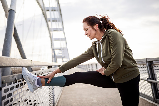 Young Caucasian woman stretching on the bridge getting ready to run
