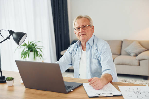 istock With laptop on table. Senior man in nice clothes is at home 1371081066