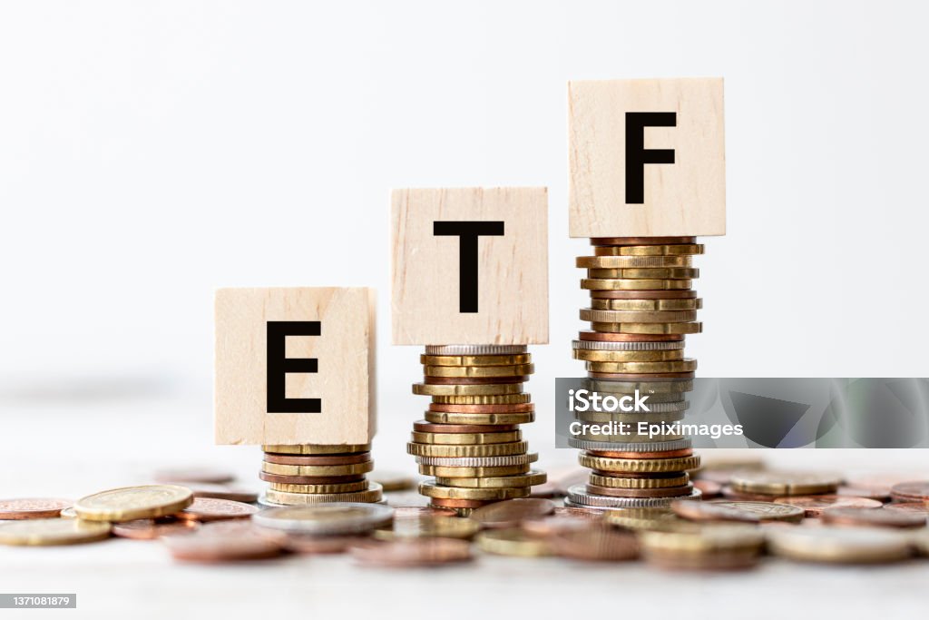 Concept - ETF Exchange Traded Fund wording on wooden cubes with coins Exchange Traded Fund (ETF) concept. Wooden cube standing with "ETF" text. "nWhite background, copy space. Exchange-Traded Fund Stock Photo