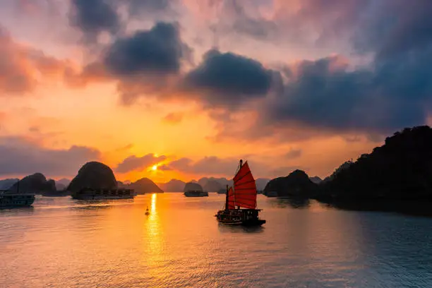 Photo of Amazing boat sailing toward the sunset over Ha Long Bay, Vietnam
