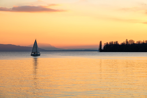 Small sailboat on Lake Geneva at sunset from the banks in Morges