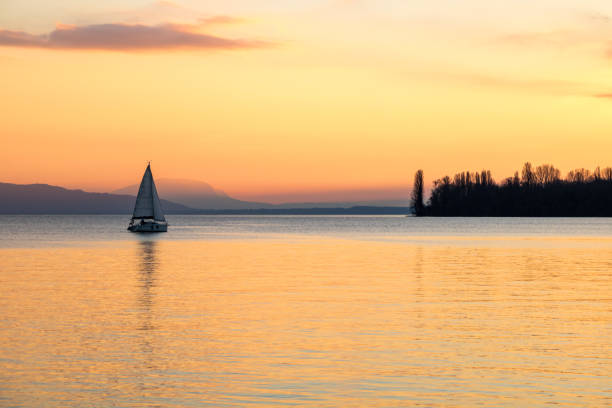 Small sailboat on Lake Geneva at sunset from the banks in Morges (Canton of Vaud, Switzerland) stock photo