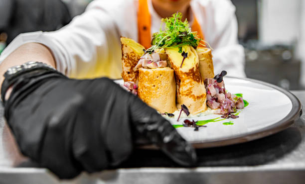istock Chef's hands in gloves cooking fried thin pancakes crepe stuffed potato with herring fish on kitchen 1371087765