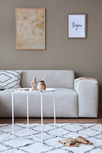 istock Modern composition in stylish living room interior with design neutral sofa, coffee table, mock up poster frames, carpet, decoration and elegant personal accessories in home decor. Template. 1371088351