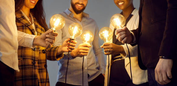 istock Happy business people holding light bulbs as metaphor for sharing ideas in creative community 1371094914