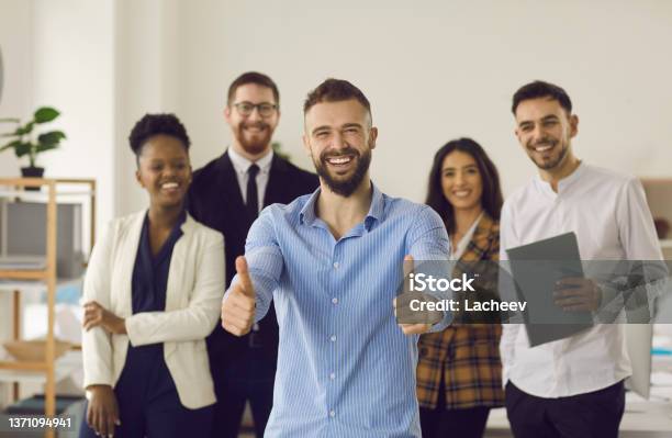 Smiling Leader Gesturing Thumbs Up Standing With Diverse Business Team In Office Stock Photo - Download Image Now